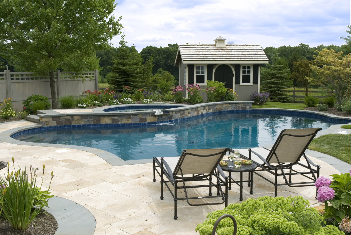 Two pool chairs sit behind an inground swimming pool.