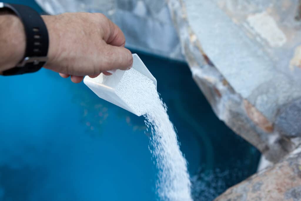 Pouring chlorine into swimming pool

