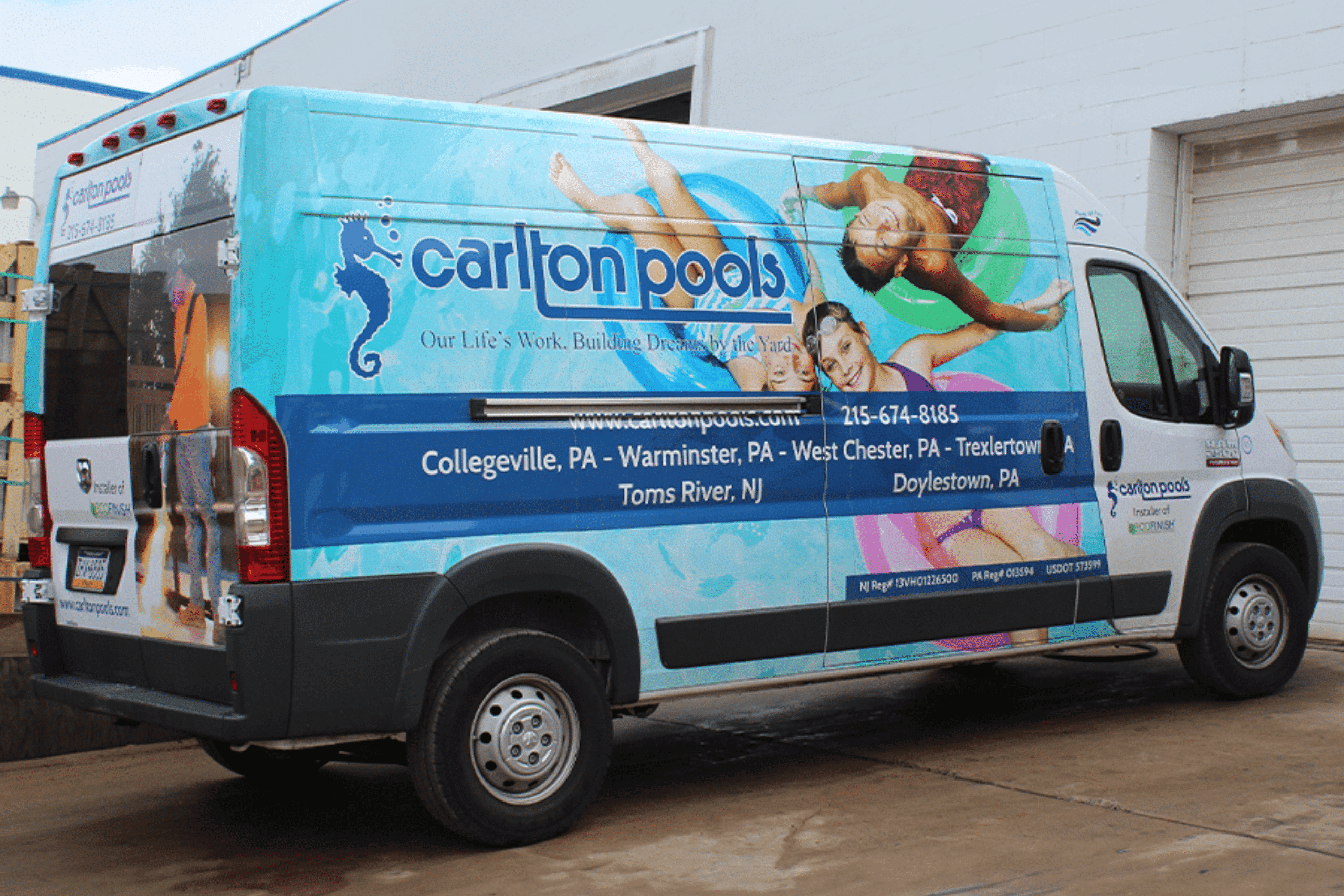A white commercial van wrapped with a bright blue and white design advertising "Carlton Pools." The wrap features a large image of three people relaxing on inner tubes in a swimming pool.